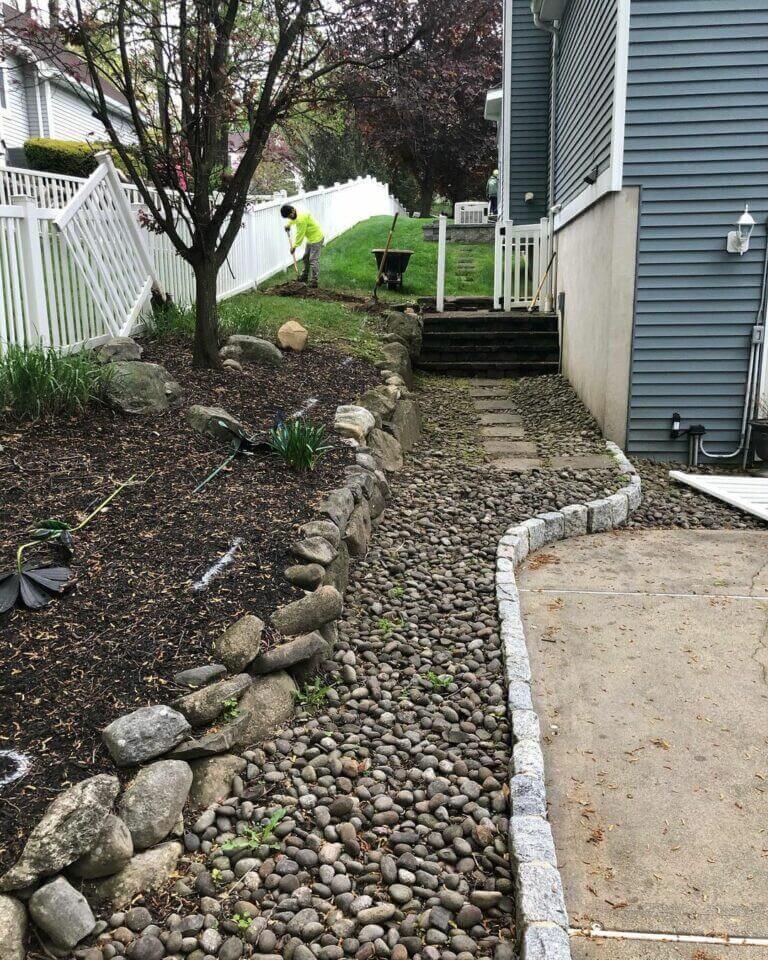 River rock bed and paver path along a house's side yard