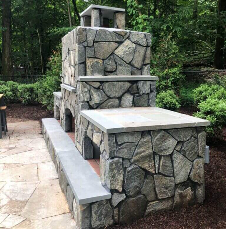Natural stone outdoor fireplace with flagstone seating wall
