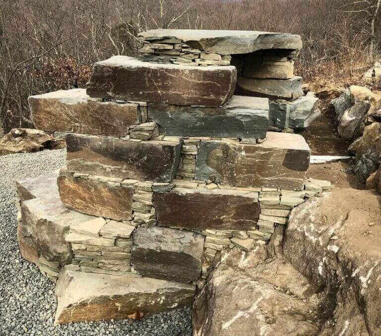 Stacked boulder retaining wall under construction