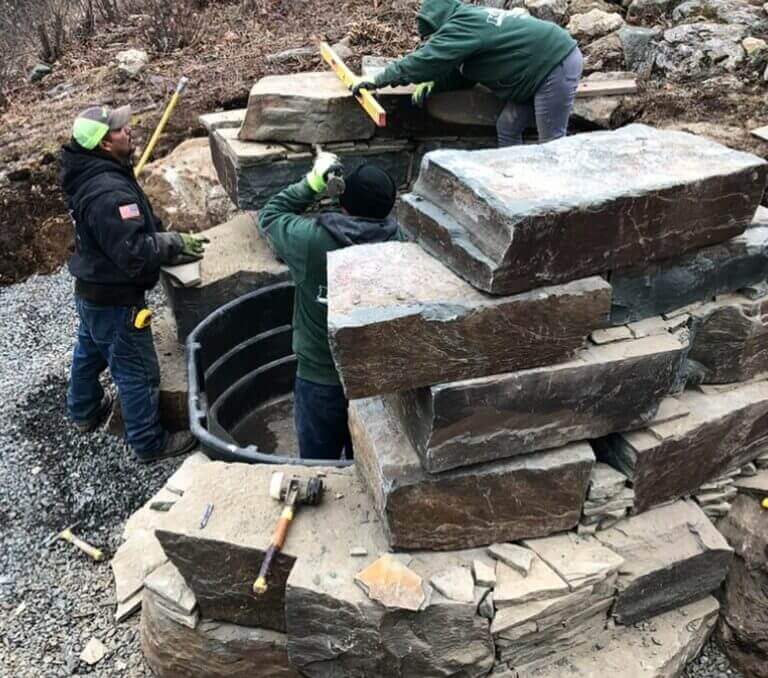 Crew setting large stone blocks for a retaining wall