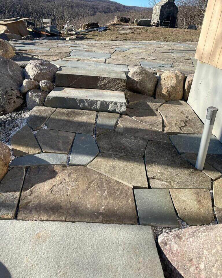 Stone steps and patio being built beside a house
