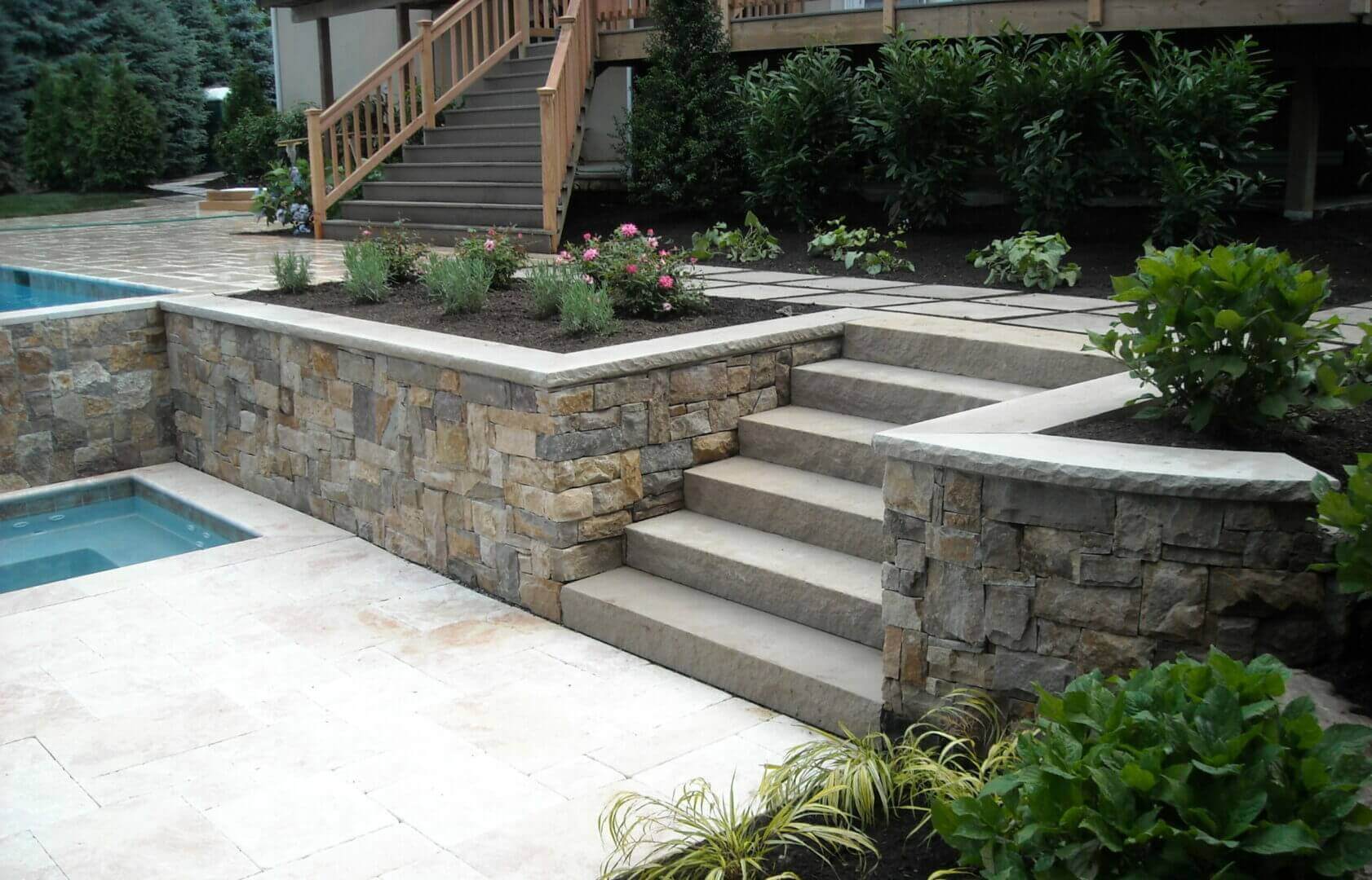Stone steps and retaining wall beside a backyard pool